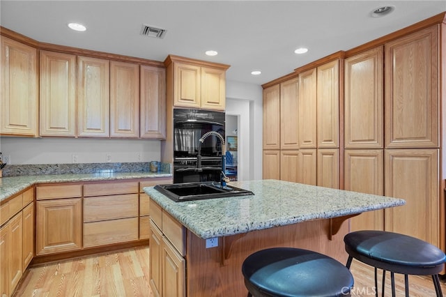 kitchen with a kitchen island, light hardwood / wood-style flooring, sink, and a breakfast bar