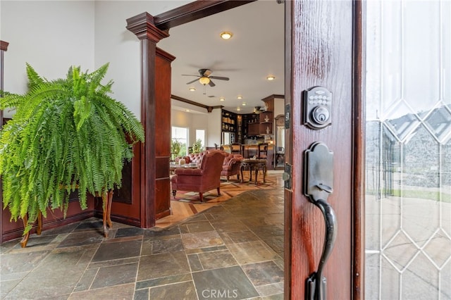 foyer with decorative columns, ceiling fan, and crown molding