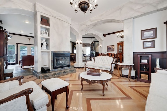 living room featuring ornamental molding, a tiled fireplace, an inviting chandelier, and parquet flooring