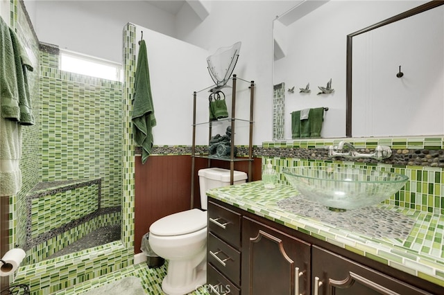 bathroom with tiled shower, vanity, and toilet