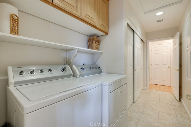 laundry area featuring separate washer and dryer, cabinets, and light tile patterned floors