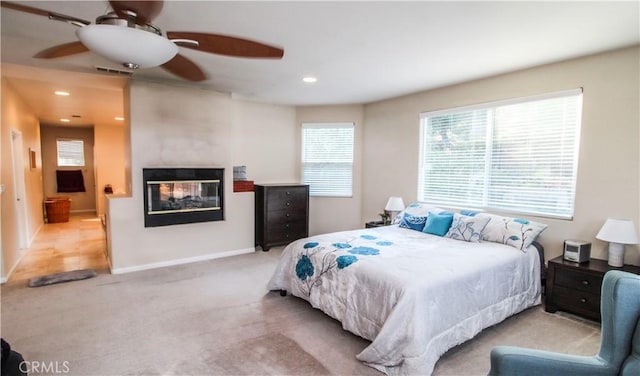 carpeted bedroom with ceiling fan and a multi sided fireplace