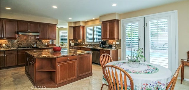 kitchen with backsplash, dark stone countertops, stainless steel dishwasher, and gas cooktop