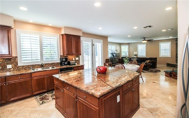 kitchen with ceiling fan, a center island, sink, and tasteful backsplash