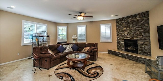 tiled living room with ceiling fan and a stone fireplace