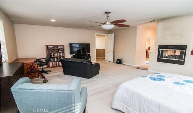 bedroom with ceiling fan, a multi sided fireplace, and carpet floors