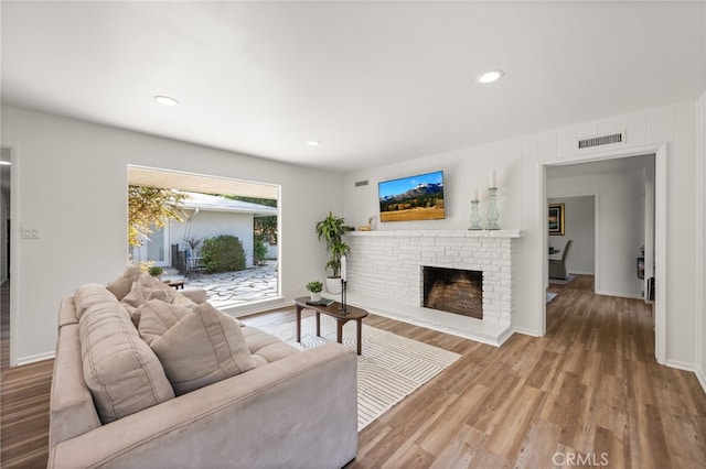 living room with hardwood / wood-style floors and a brick fireplace