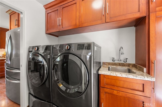 laundry area with washing machine and dryer, sink, light hardwood / wood-style flooring, and cabinets