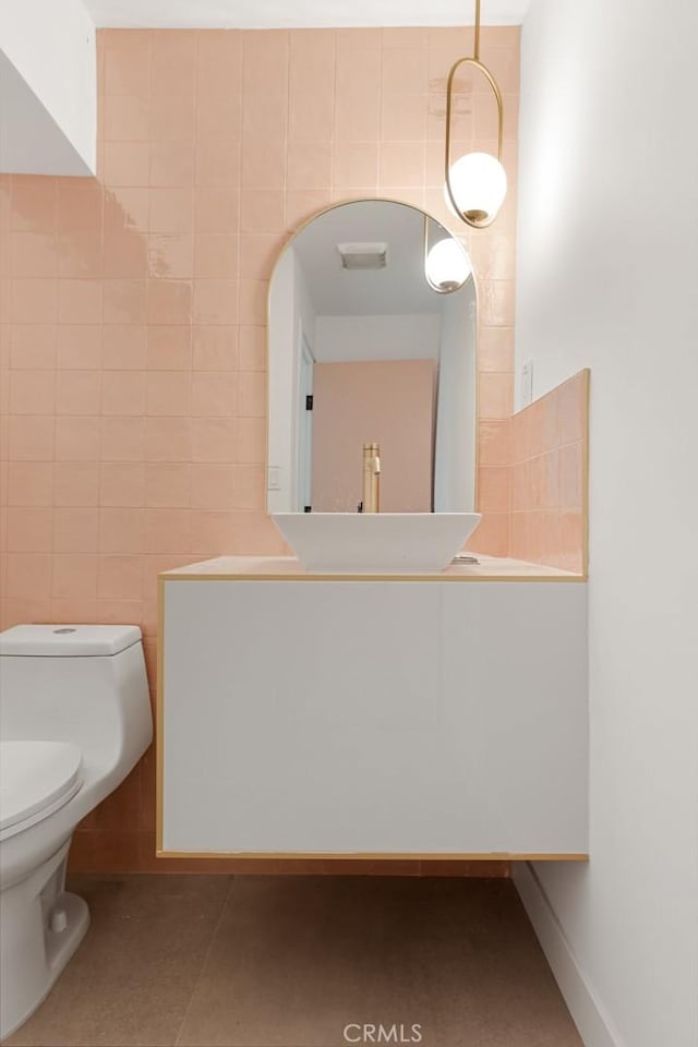 bathroom with sink, tile walls, and toilet