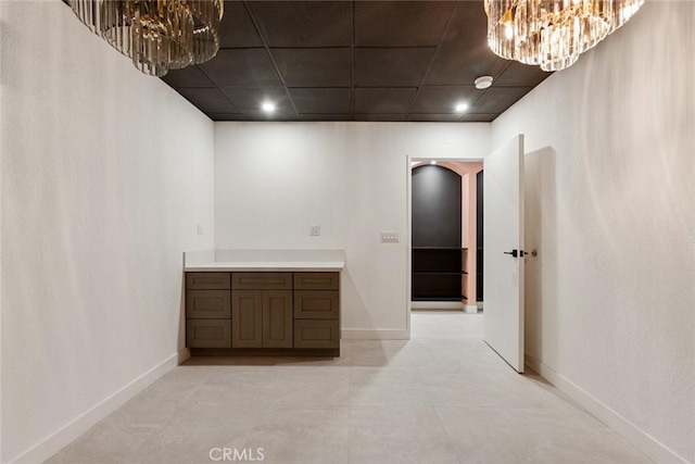 corridor featuring a paneled ceiling and an inviting chandelier