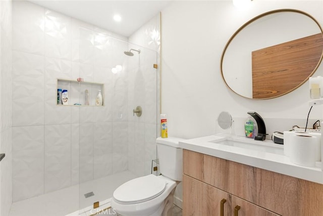 bathroom featuring a tile shower, vanity, and toilet