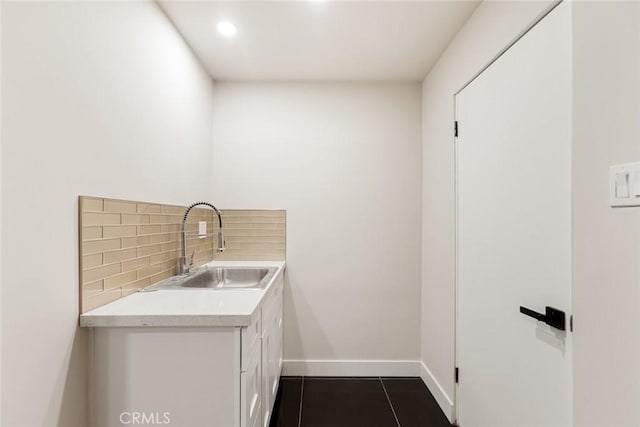 laundry room featuring sink and dark tile patterned floors