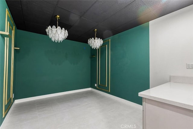 spare room featuring a paneled ceiling and a notable chandelier