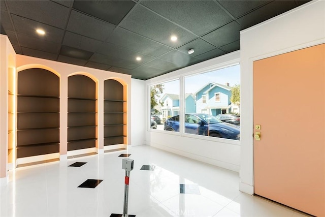 exercise area with a paneled ceiling and light tile patterned flooring