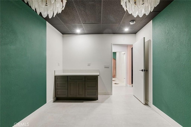 corridor with a chandelier and a paneled ceiling