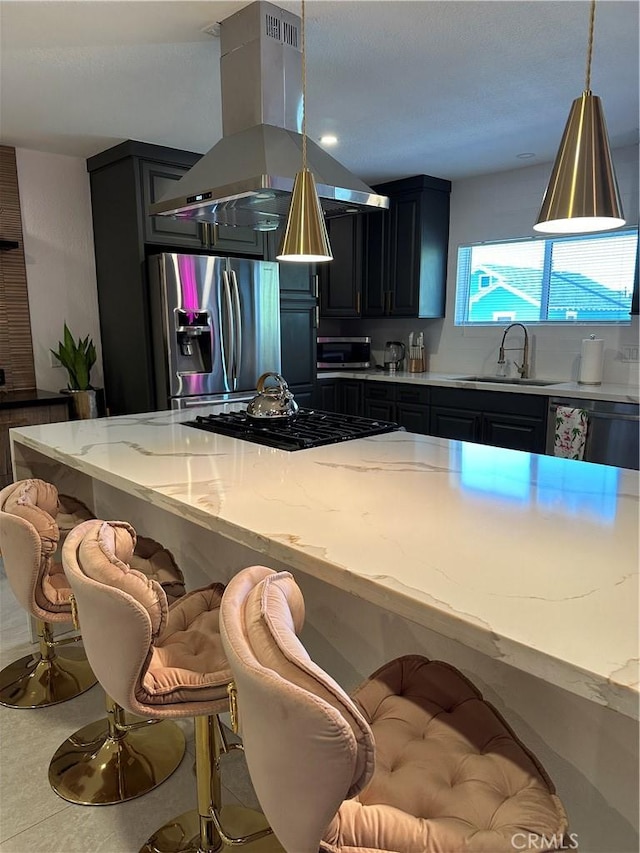 kitchen with island exhaust hood, light stone counters, sink, and appliances with stainless steel finishes