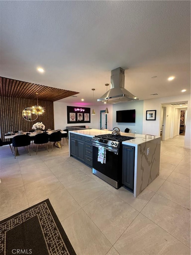 kitchen with gas range, a textured ceiling, hanging light fixtures, and wall chimney exhaust hood