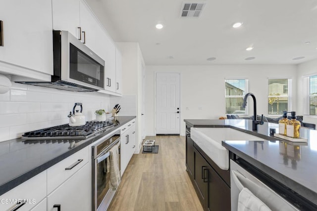 kitchen featuring white cabinets, appliances with stainless steel finishes, and light hardwood / wood-style flooring