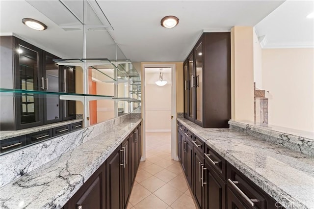 interior space with light stone counters, pendant lighting, light tile patterned floors, and dark brown cabinetry