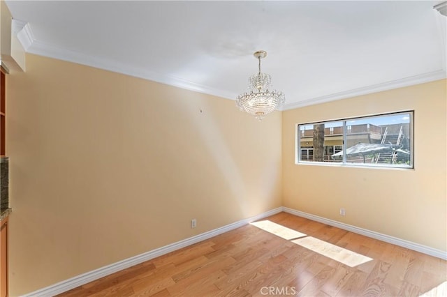 empty room with crown molding, an inviting chandelier, and light hardwood / wood-style flooring