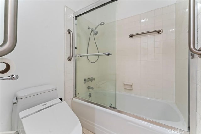 bathroom with toilet and shower / bath combination with glass door