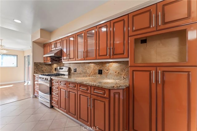 kitchen with light stone countertops, an inviting chandelier, decorative backsplash, light tile patterned floors, and stainless steel range with gas stovetop