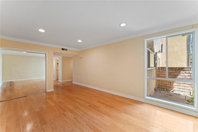 spare room featuring ornamental molding and light hardwood / wood-style flooring