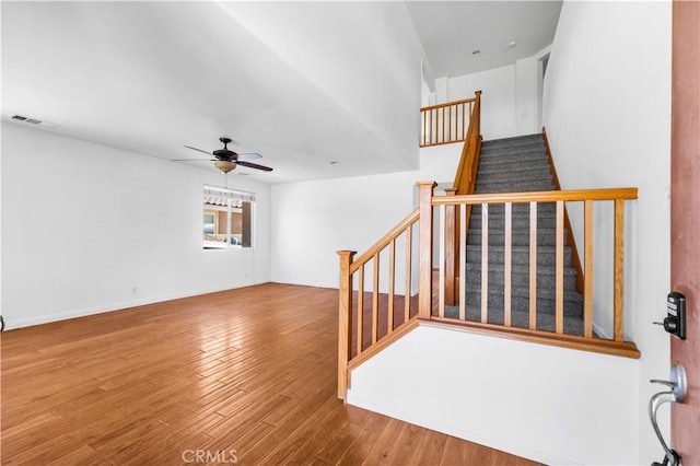 stairway with wood-type flooring and ceiling fan