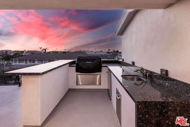 patio terrace at dusk featuring grilling area and sink