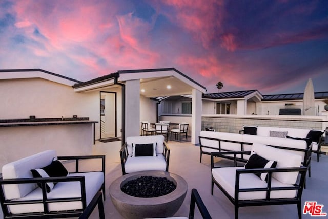 patio terrace at dusk with an outdoor living space with a fire pit