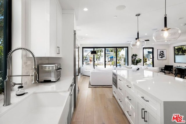 kitchen featuring light hardwood / wood-style floors, sink, white cabinetry, stainless steel appliances, and decorative light fixtures