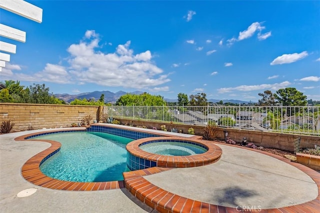 view of swimming pool with a patio area, a mountain view, and an in ground hot tub