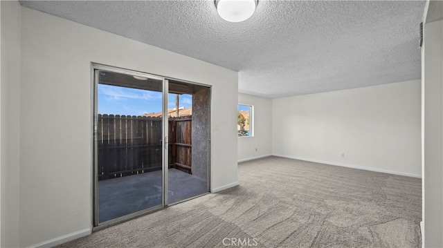 carpeted empty room featuring a textured ceiling