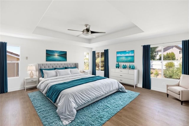 bedroom featuring a raised ceiling, ceiling fan, and hardwood / wood-style flooring