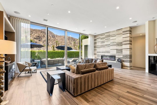 living room with light hardwood / wood-style flooring, floor to ceiling windows, a mountain view, and a tile fireplace