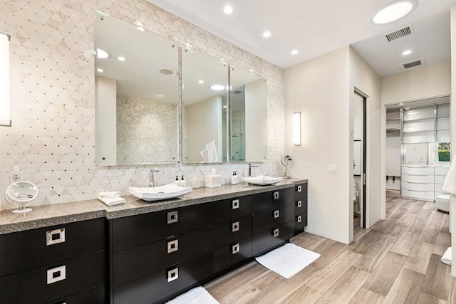 bathroom featuring decorative backsplash, hardwood / wood-style flooring, and vanity