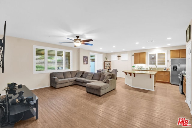 living room with ceiling fan, light wood-type flooring, and sink