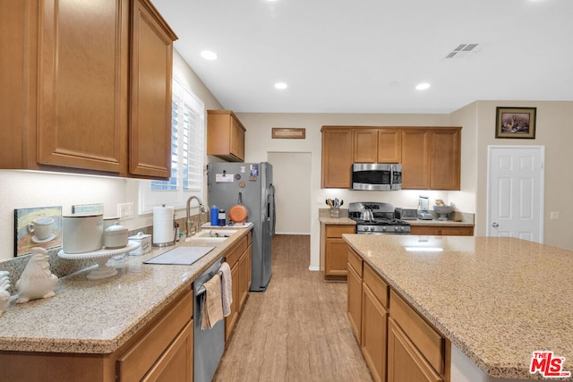 kitchen featuring light wood-type flooring, a kitchen island, sink, and stainless steel appliances