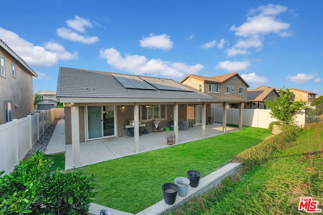 rear view of property with solar panels, a yard, and a patio