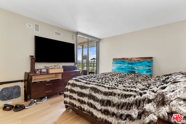 bedroom featuring a wall of windows and light hardwood / wood-style flooring