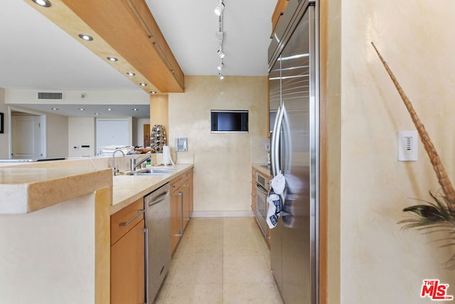 kitchen featuring rail lighting, kitchen peninsula, appliances with stainless steel finishes, and sink