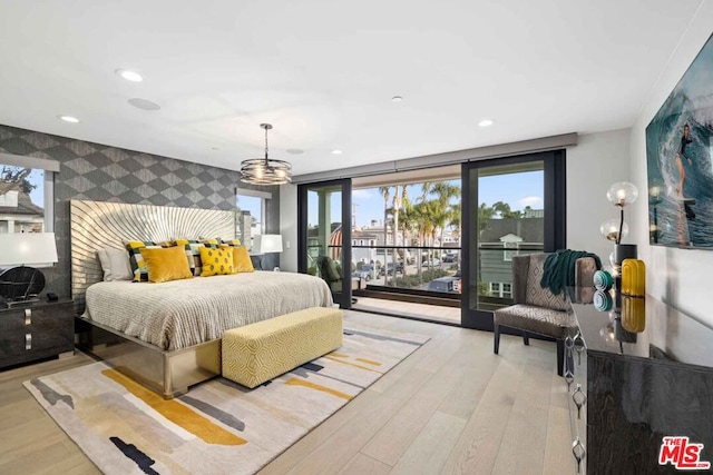 bedroom featuring access to outside, light hardwood / wood-style floors, and an inviting chandelier