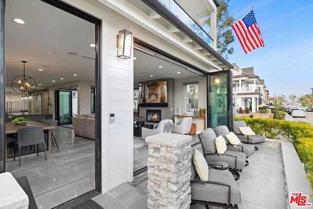 view of patio / terrace with a balcony and an outdoor stone fireplace