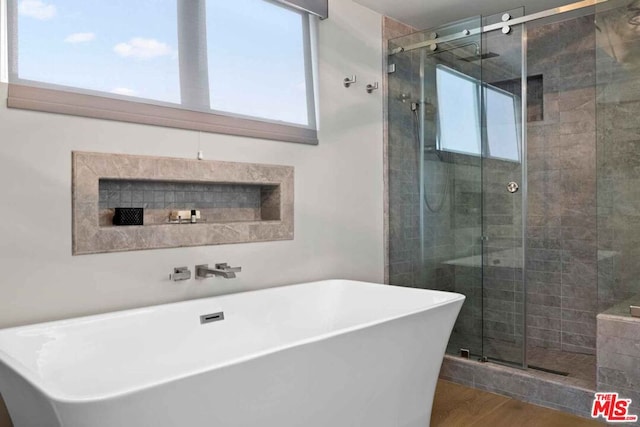 bathroom featuring plus walk in shower and hardwood / wood-style floors