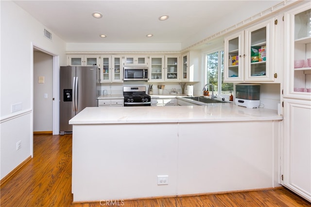 kitchen featuring appliances with stainless steel finishes, sink, kitchen peninsula, and light hardwood / wood-style flooring