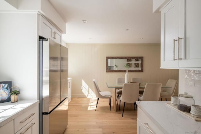 dining room featuring light wood-type flooring and wood walls