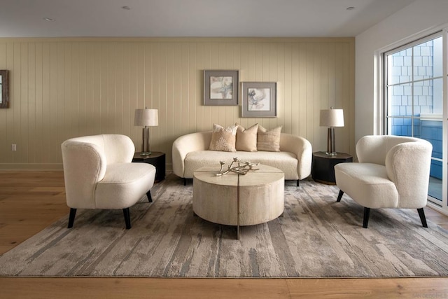 sitting room with hardwood / wood-style flooring and wood walls