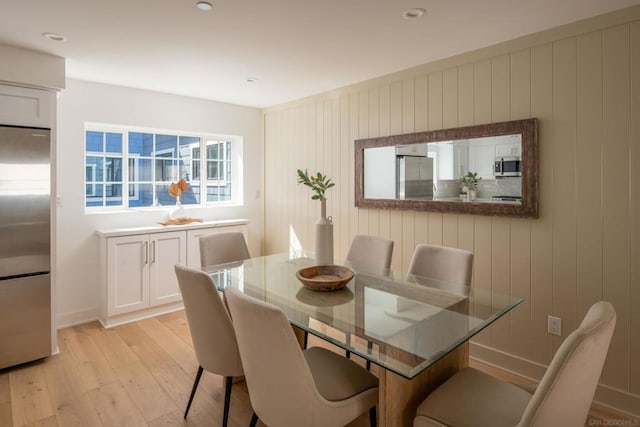 dining area with wood walls and light wood-type flooring