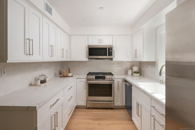 kitchen with stainless steel appliances, white cabinetry, and sink