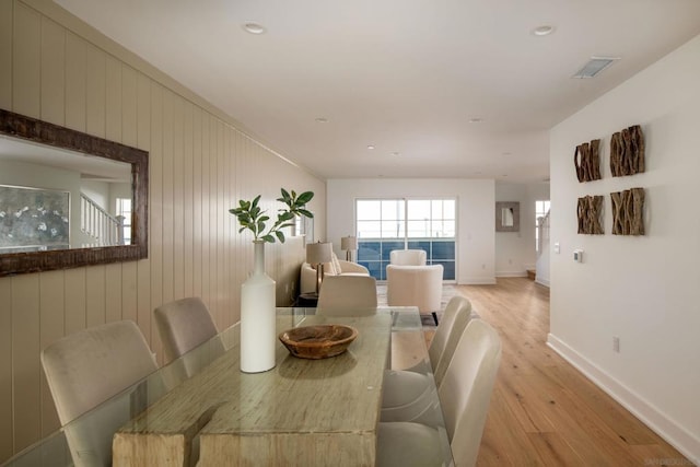 dining room featuring light hardwood / wood-style flooring and wooden walls